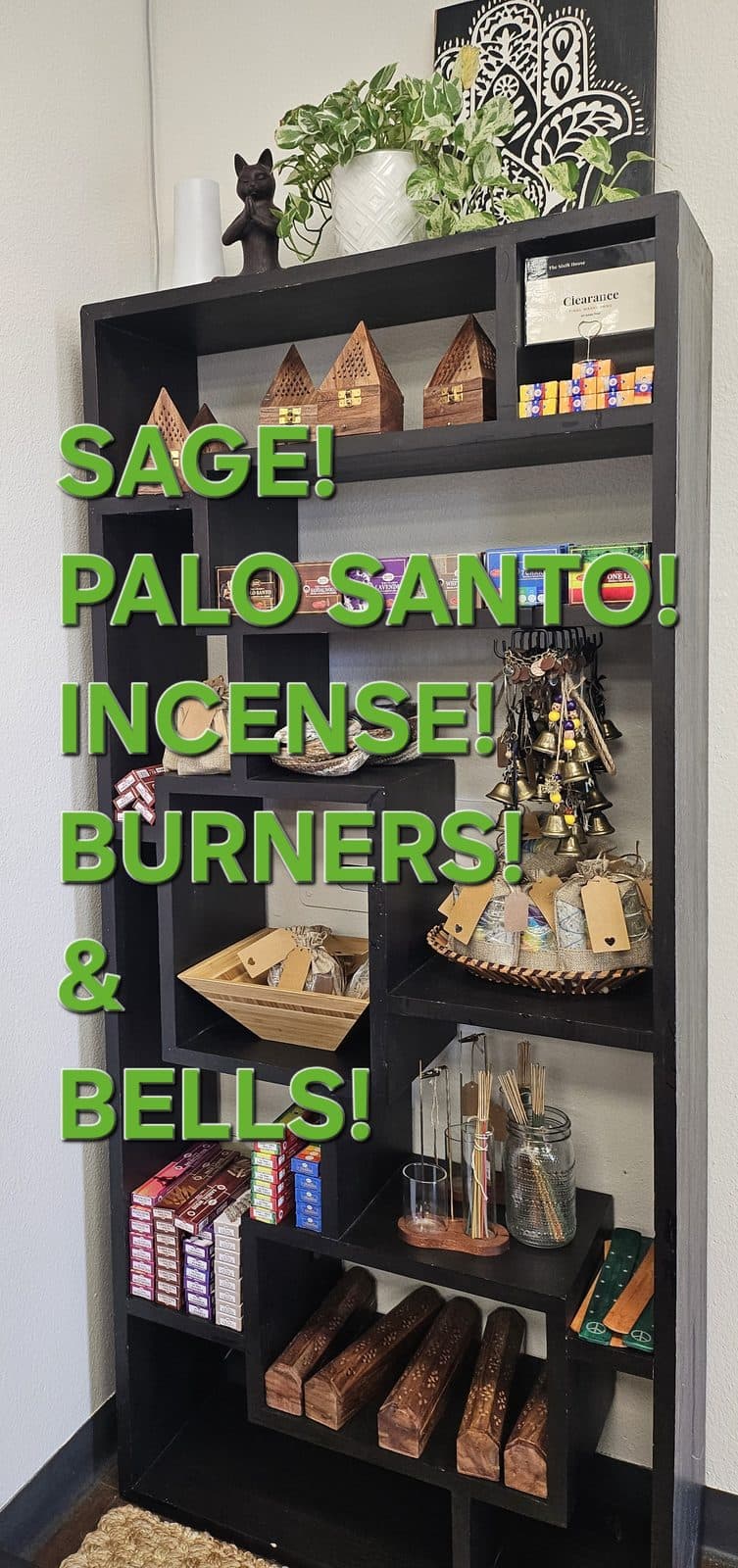 A tall black shelf unit of sage bundles, incense, burners and bells, captioned “Sage! Palo santo! Incense! Burners! & Bells!”.
